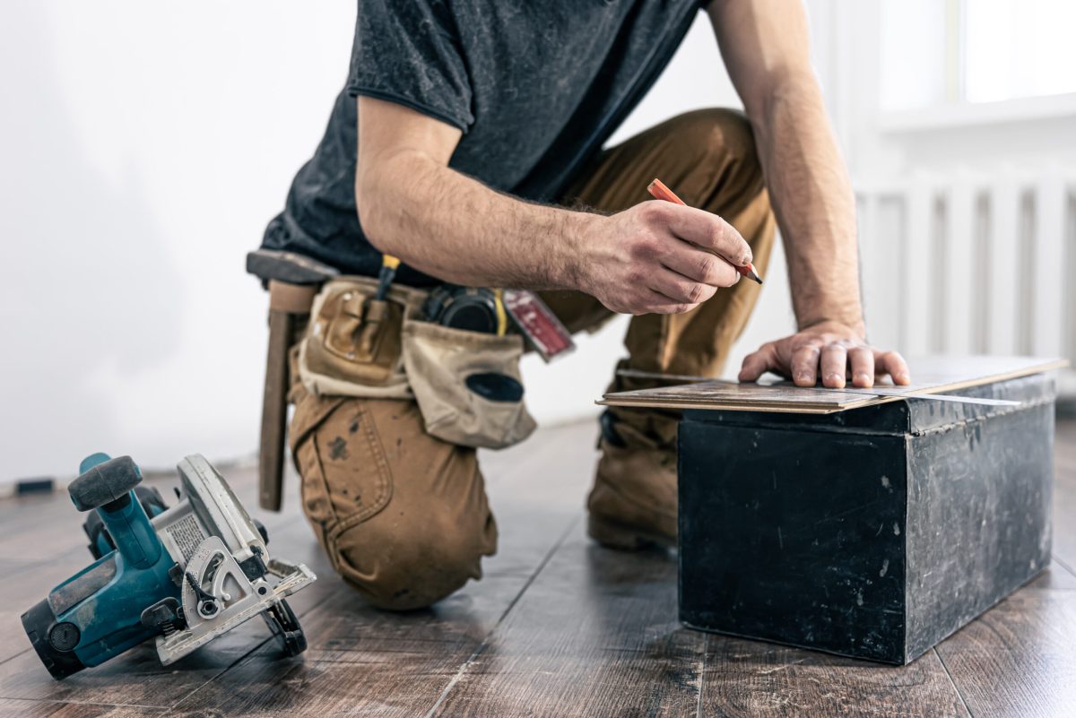 Building contractor worker using hand held worm drive circular saw to cut boards on a new home constructiion project.